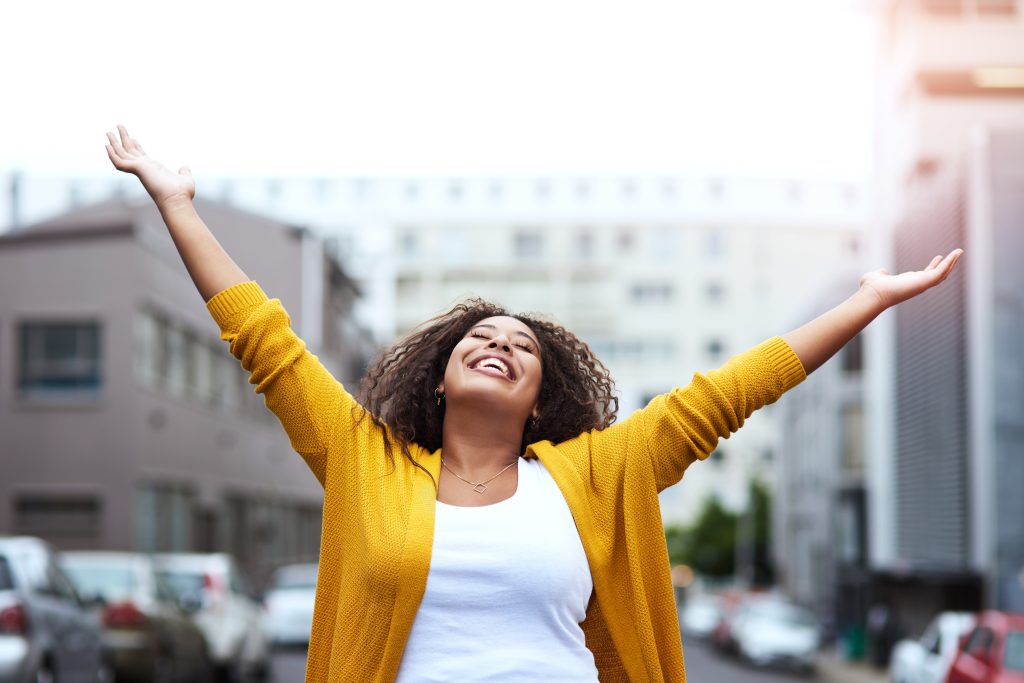 A woman joyfully raises her arms in the air, expressing excitement or celebration.