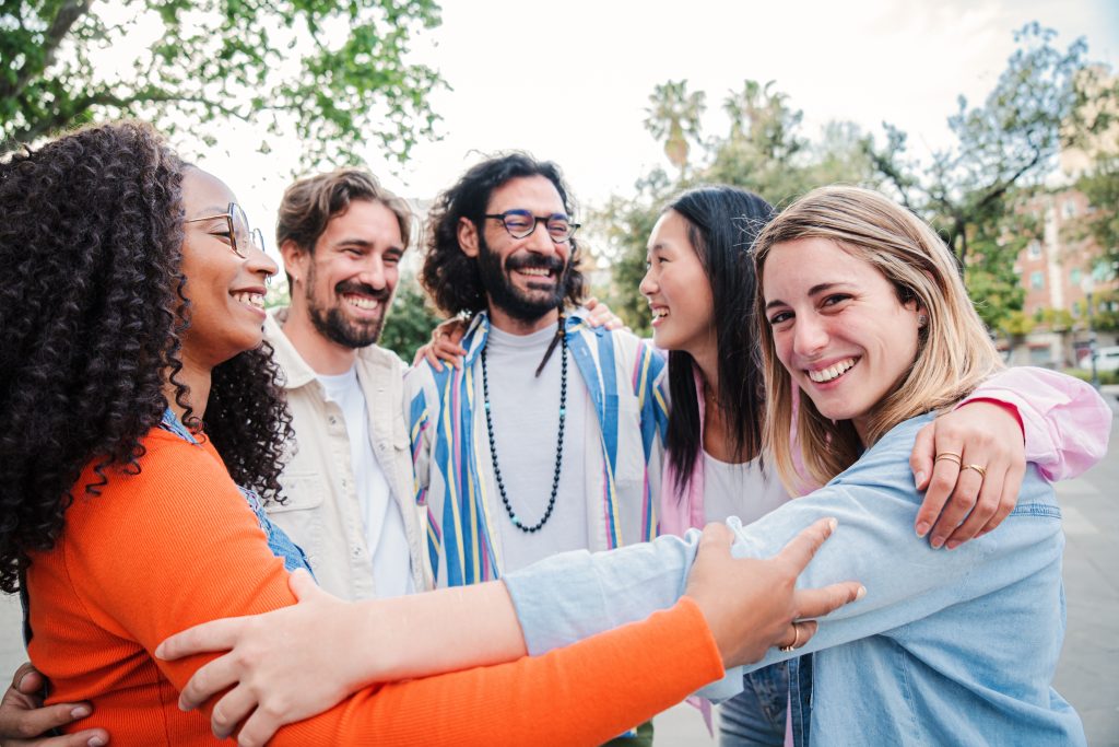 A joyful group of friends hugging each other and smiling warmly, celebrating their friendship together.