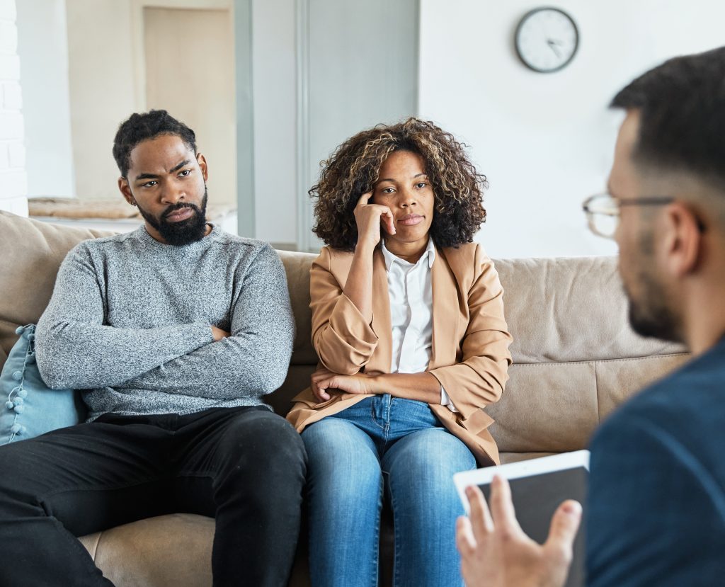 A man and woman relax on a couch, with the man focused on Understanding the Impact of Marijuana.