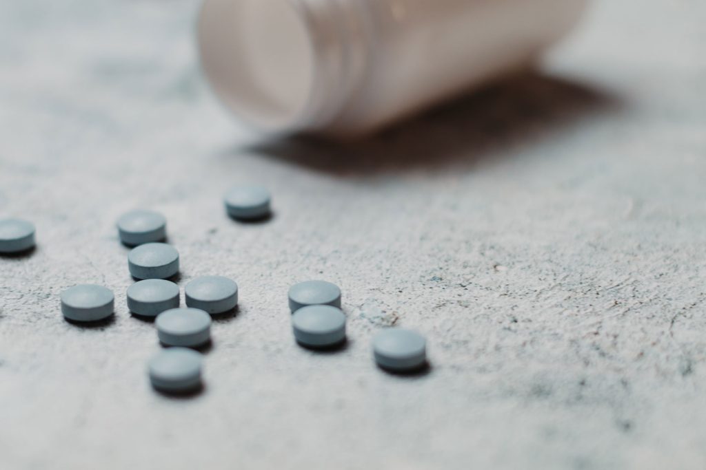 Blue pills on spread out on concrete.