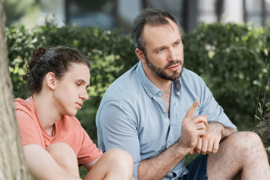 Bearded father talking to his son outdoor.