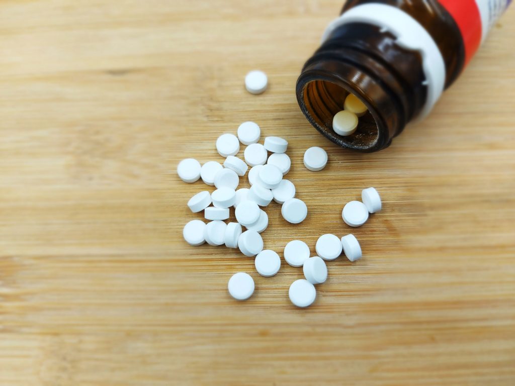 Close-up of white pills scattered in wooden floor.