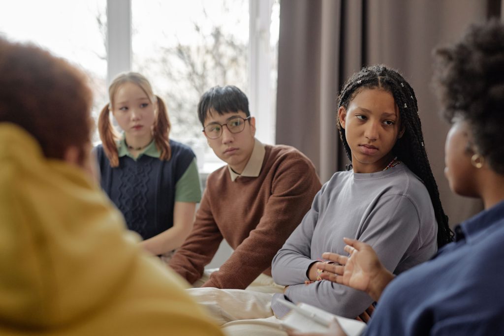 Diverse teens listening to a psychologist to improve mental health.