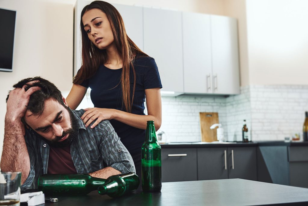 Wife consoling his husband with alcohol addiction.