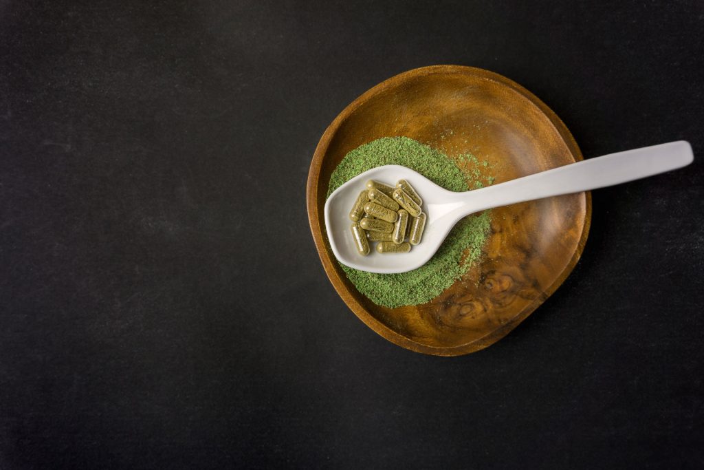 Kratom pills and powder in a plate.