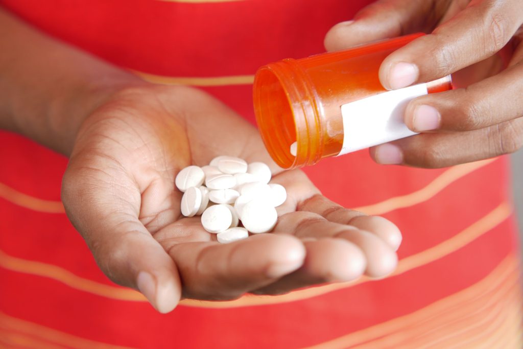 Man spilling out pills from a bottle.