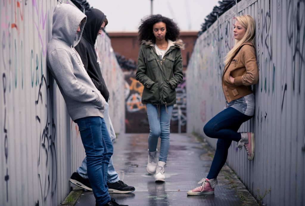 Teenagers standing against a wall with grafitti.