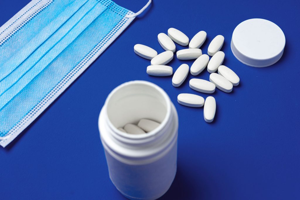 White pills and facemask in blue background.