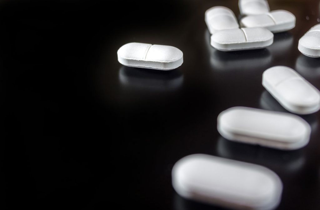 White pills isolated in black background.