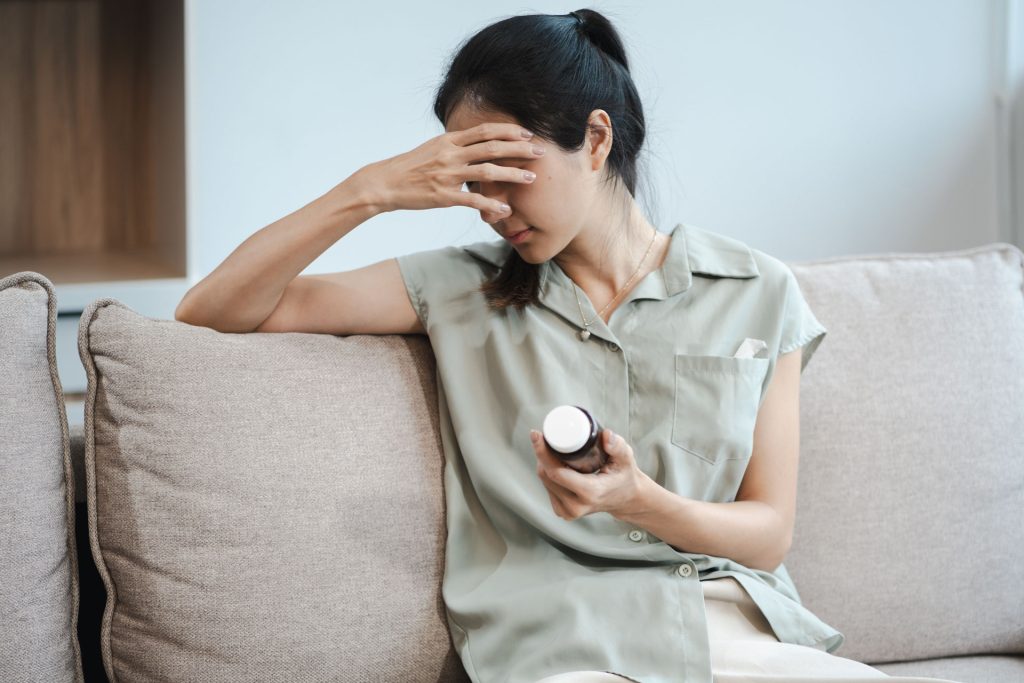 Woman sitting in sofa holding a pill container.