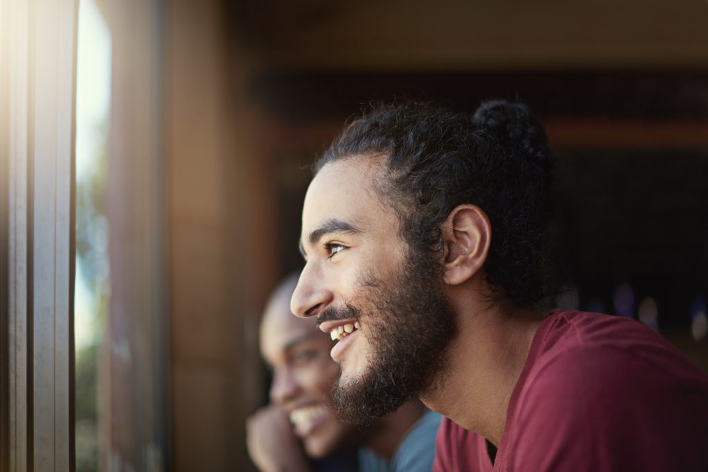 Two men with Depression standing by a window, looking outside with curiosity and contemplation. 