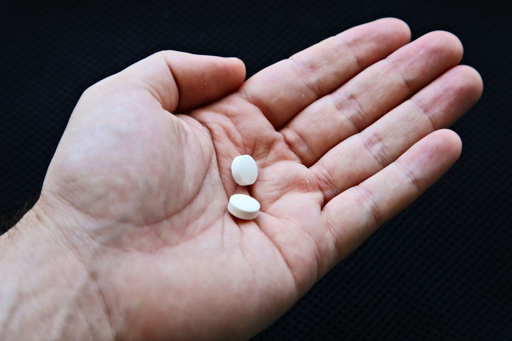 Person holding a white pill.