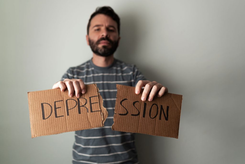 Adult man holding cardboard with depression written on it.