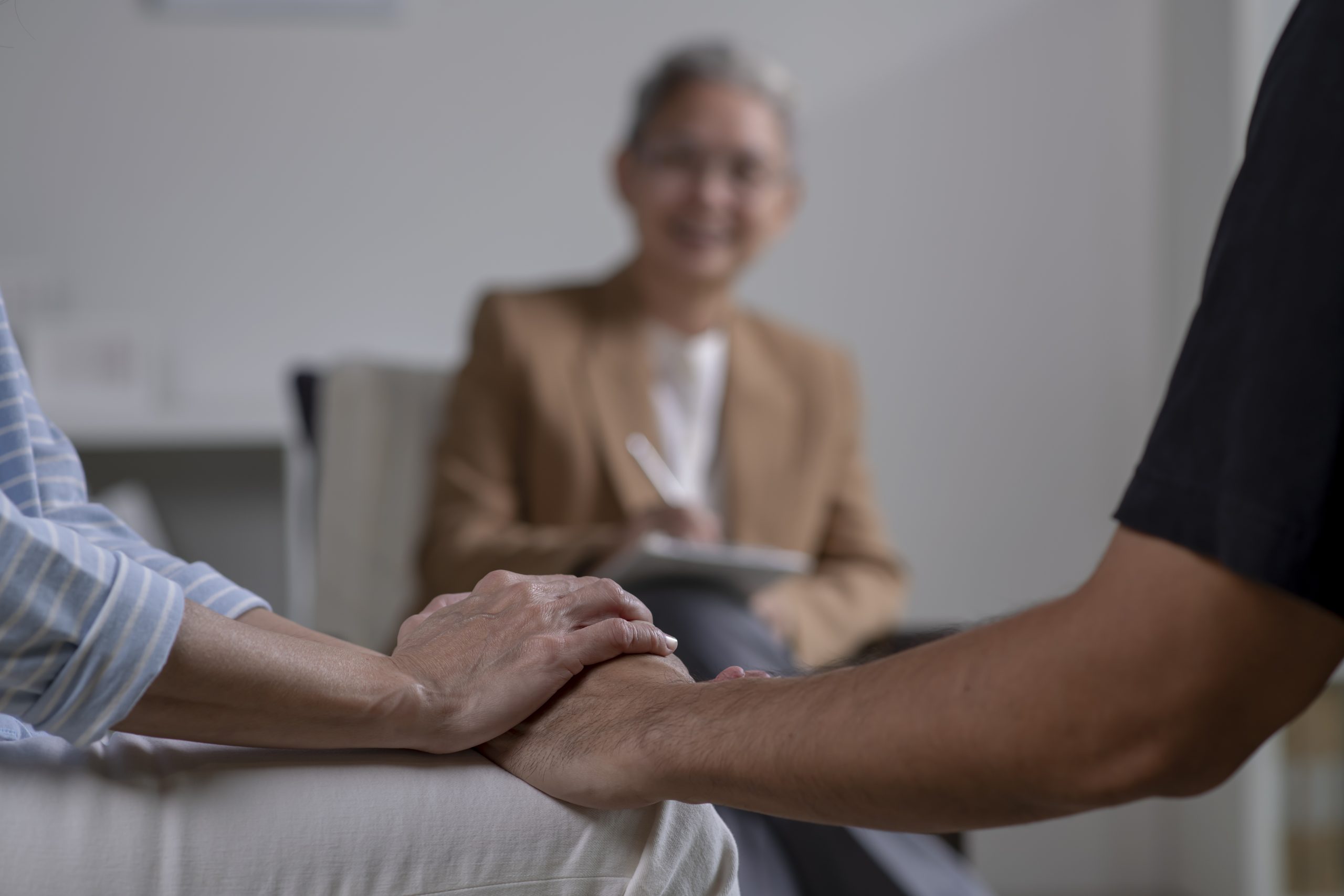 A man and woman hold hands, standing together in front of another person, creating a sense of connection and unity for Smoking Cessation Program.