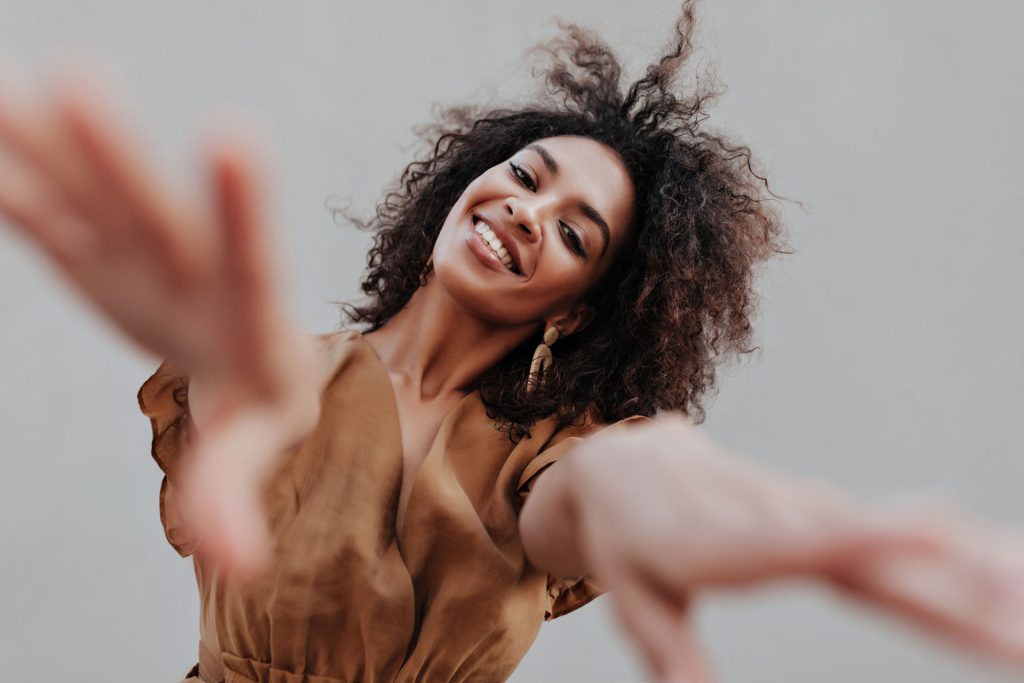 Smiling woman stretches arms to camera.